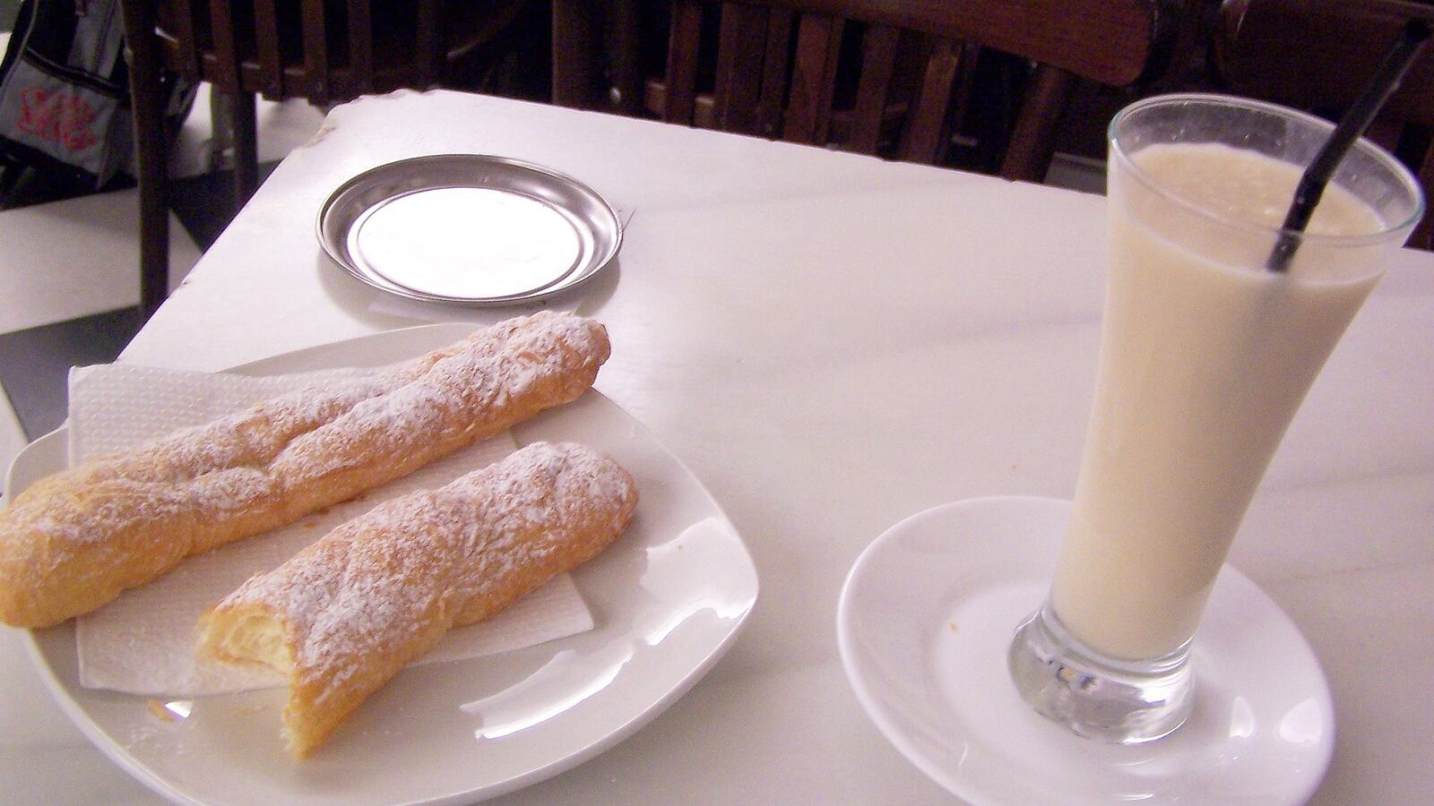 Een glas horchata met twee fartons op een schoteltje