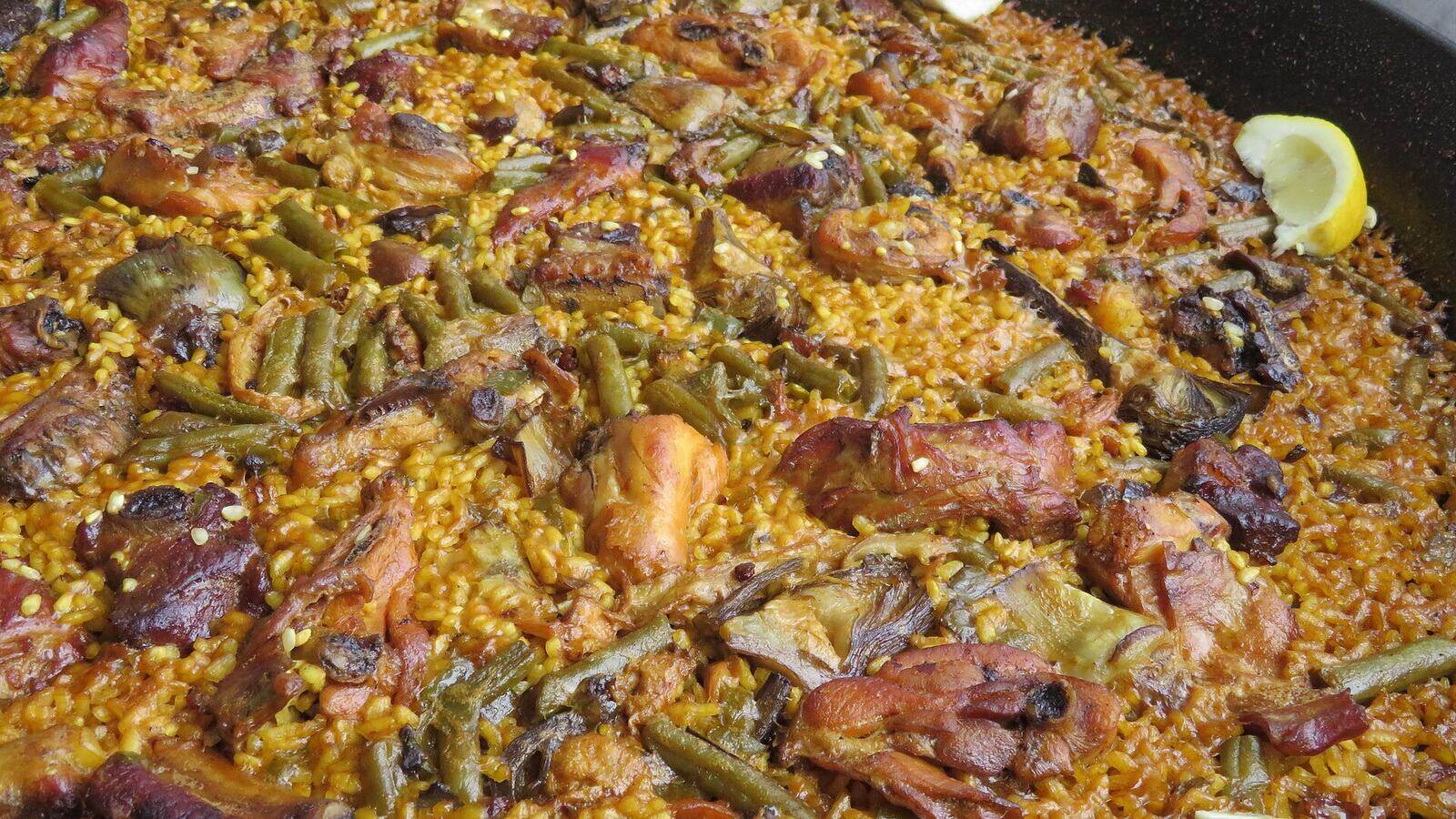 Een grote pan paella valenciana met rijst, kip en groenten